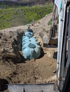 Installation of multiple low-profile polyethylene septic tanks for a large uniform distribution sand mound system in a wildfire-affected area of the Okanagan.