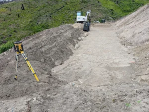 Preparation of the sand bed for a uniform distribution sand mound septic system, using a laser level for precision grading in a wildfire recovery zone.