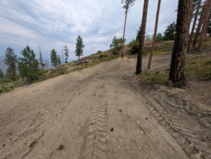 Final site grading and restoration after a large Type 2 septic system installation on a steep hillside property overlooking Okanagan Lake.