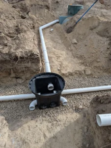 Installation of a septic distribution box (D-box) connecting the tank to gravity trenches, ensuring even effluent flow for a residential system in the Okanagan.